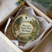 A decorative ornament in a box, featuring a scenic landscape with a lighthouse and trees, with the text "McLain State Park, Michigan" printed on it.