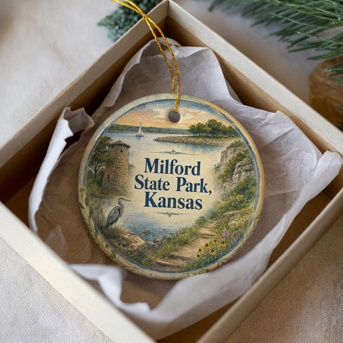 A decorative ornament in a box, featuring a scenic landscape with a lake, a castle, and a bird, along with the text "Milford State Park, Kansas".
