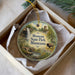 A decorative ornament in a box, featuring a scenic landscape with a waterfall, trees, and a bison.