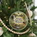 A circular ornament hanging on a Christmas tree, featuring a scenic landscape with a waterfall, a bridge, and a bison in the foreground.