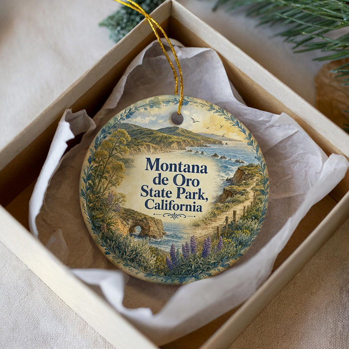A decorative ornament in a box, featuring a scenic landscape with mountains, water, and greenery.