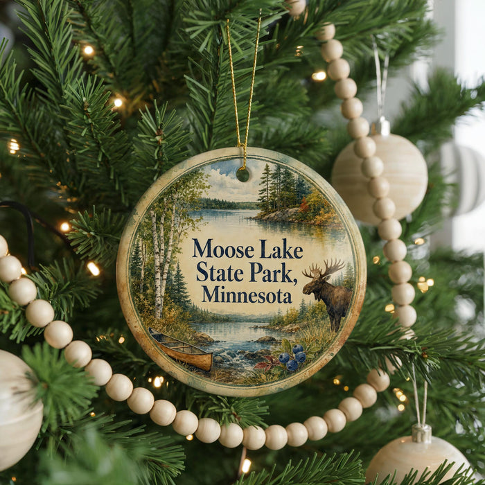 A round ornament hanging on a Christmas tree, featuring a scenic image of Moose Lake State Park, Minnesota.