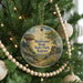 A round ornament hanging on a Christmas tree, featuring a scenic landscape with a mushroom-shaped rock formation and a path leading through the field.