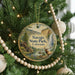 A round ornament hanging on a Christmas tree, featuring a scenic landscape with a waterfall and a deer.