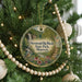 A round ornament hanging on a Christmas tree, featuring a scenic image of a waterfall surrounded by flowers and greenery.