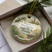 A decorative ornament in a box, featuring a scenic image of North Peninsula State Park, Florida.