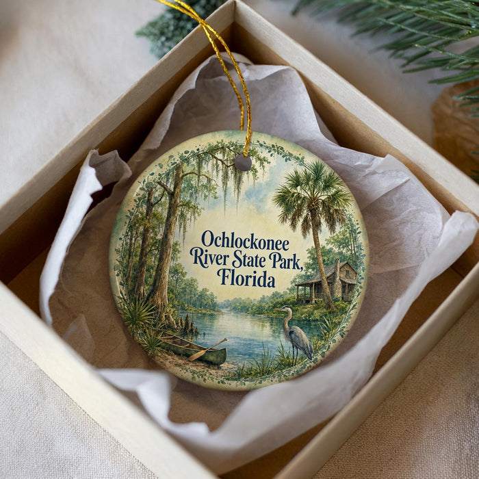 A decorative ornament in a white box, featuring a scenic image of Ochlockonee River State Park in Florida.