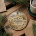 A circular ornament with a desert landscape and a vehicle, hanging on a wooden surface.
