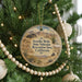 A circular ornament hanging on a Christmas tree, featuring a desert landscape with a vehicle and mountains in the background.