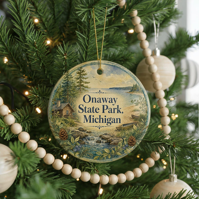 A round ornament hanging on a Christmas tree, featuring a scenic landscape with a cabin and a lake.