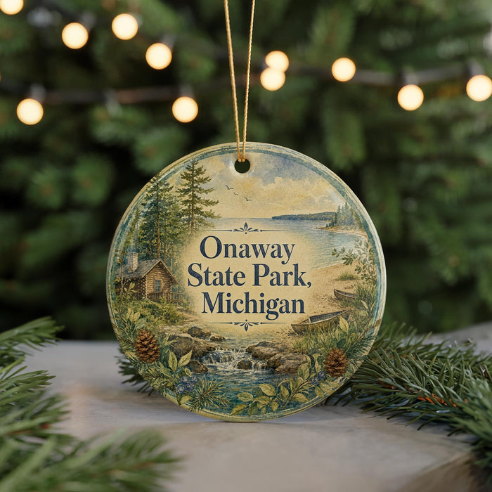 A round ornament with a scenic landscape of Onaway State Park, Michigan, featuring a cabin, pine trees, and a waterfall.