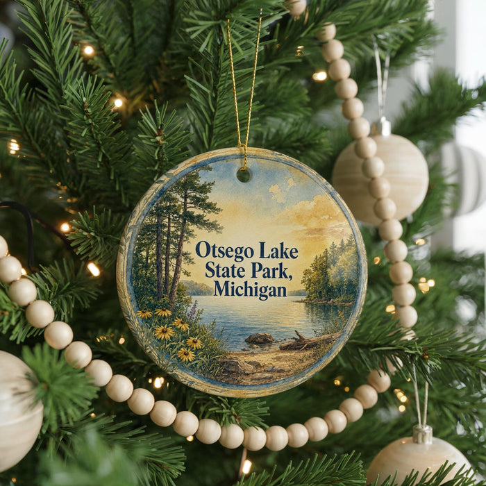 A round ornament hanging on a Christmas tree, featuring a scenic landscape with a lake and trees.