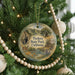 A round ornament on a Christmas tree, featuring a scenic landscape with mountains, trees, and a river.