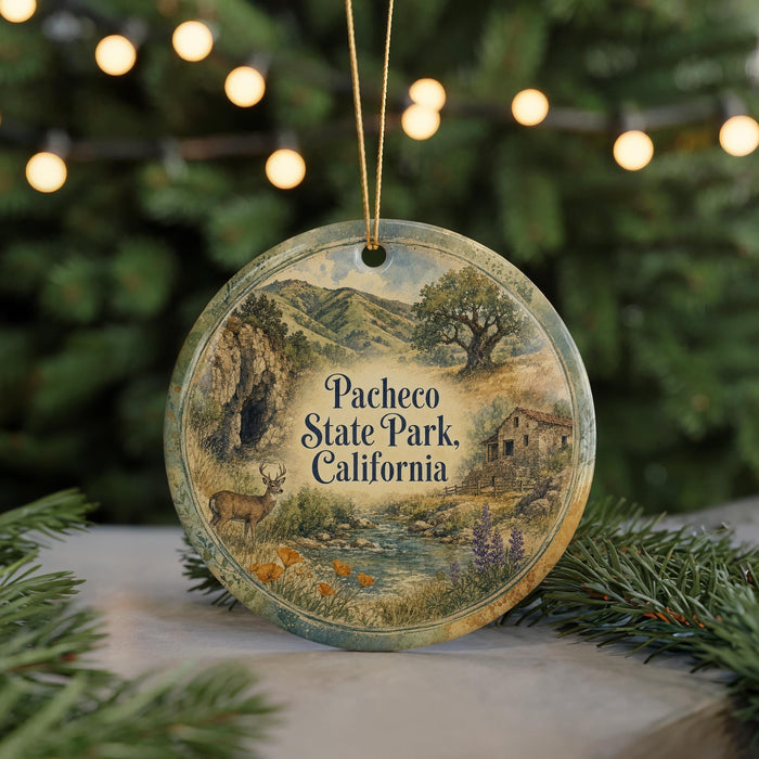 A decorative ornament featuring a scenic landscape with mountains, trees, and a stream, hanging in front of a Christmas tree with twinkling lights.