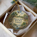 A circular ornament with a painting of palm trees, a bird, and a house, along with the text "Palmetto Island State Park, Louisiana" printed on it.
