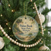 A round ornament hanging on a Christmas tree, featuring a scenic landscape with a lake and mountains.