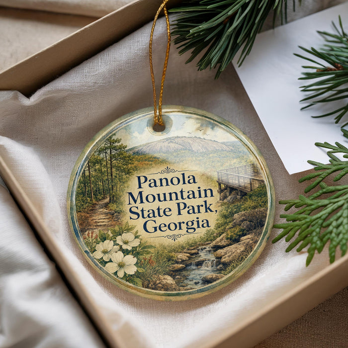 A decorative ornament with a scenic landscape of Panola Mountain State Park, Georgia, featuring a winding path, trees, and a waterfall.
