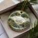 A decorative ornament in a box, featuring a scenic image of Patuxent River State Park, Maryland.