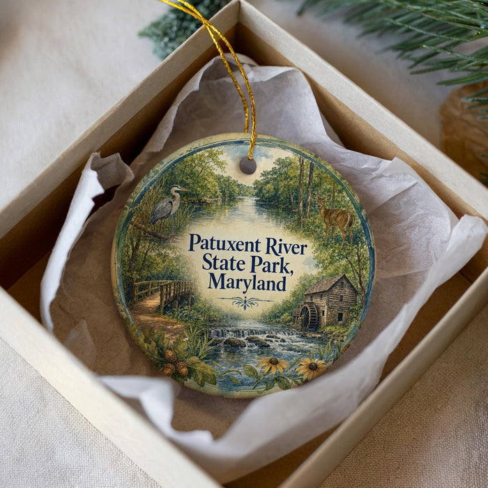 A decorative ornament in a white box, featuring a scenic image of Patuxent River State Park, Maryland.