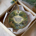 A decorative ornament in a white box, featuring a scenic image of Patuxent River State Park, Maryland.