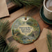 A decorative ornament featuring a scenic image of Patuxent River State Park, Maryland, surrounded by pine branches and a cup of coffee on a wooden surface.