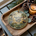 A decorative ornament with a bird and a bison, surrounded by pine cones and a lit candle, placed on a wooden tray.