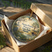 A circular ornament in a wooden box, featuring a scenic landscape with a bird, palm tree, and water, along with the text "Paynes Prairie Preserve State Park, Florida".