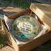 A decorative ornament in a wooden box, featuring a scenic image of Peacock Springs State Park in Florida.