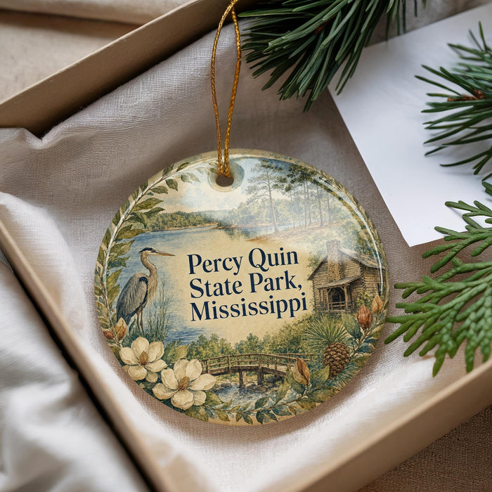 A decorative ornament with a bird and flowers, hanging from a string, placed inside a box with pine branches.