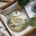 A decorative ornament with a beach scene and a bird, placed in a box with pine branches.