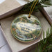 A decorative ornament in a box, featuring a scenic image of the state park in Illinois.
