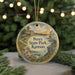 A round ornament with a painting of Perry State Park, Kansas, hanging from a string.