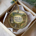 A decorative ornament in a box, featuring a scenic landscape with a waterfall and a bridge.