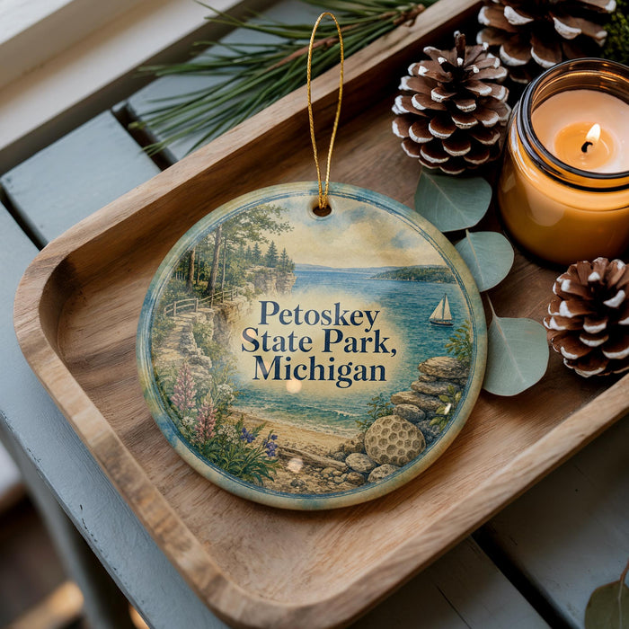A decorative ornament featuring a scenic image of Petoskey State Park in Michigan, with pine cones and a candle on a wooden tray.
