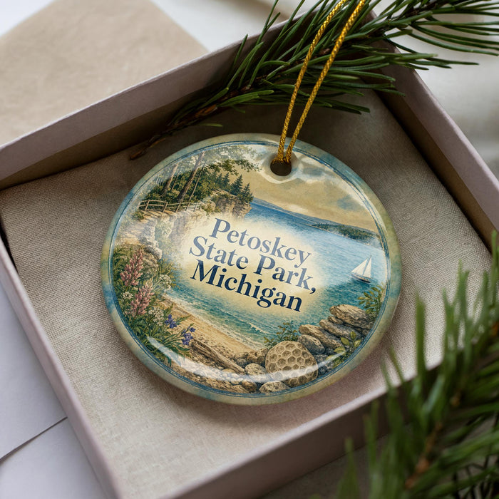 A decorative ornament in a box, featuring a scenic image of Petoskey State Park, Michigan.