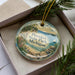 A decorative ornament in a box, featuring a scenic image of Petoskey State Park, Michigan.