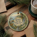 A decorative ornament with a scenic landscape of Big Sur State Park, California, featuring pine trees, a waterfall, and a river.