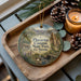 A decorative ornament featuring a scenic image of Placerta Canyon State Park, California, with pine cones and a lit candle on a wooden tray.
