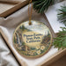 A decorative ornament with a scenic landscape of Plumas-Eureka State Park, California, featuring a waterfall, pine trees, and a cabin.