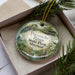 A decorative ornament in a box, featuring a scenic image of the Potomoke River State Park in Maryland.
