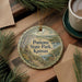 A decorative ornament with the text "Pomona State Park, Kansas" on it, surrounded by pine branches and a cup of coffee on a wooden surface.
