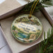 A decorative ornament in a box, featuring a scenic image of Ponce de Leon Springs State Park, Florida.