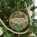A round ornament hanging on a Christmas tree, featuring a scenic image of Ponce de Leon Springs State Park in Florida.