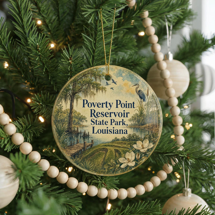 A round ornament hanging on a Christmas tree, featuring a scenic landscape with a river, trees, and birds.