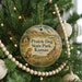A round ornament hanging on a Christmas tree, featuring a scenic image of a prairie dog in a field with mountains in the background.