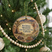 A round ornament hanging on a Christmas tree, featuring a desert landscape with mountains in the background.
