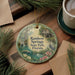A decorative ornament featuring a scenic image of Rainbow Springs State Park in Florida, surrounded by pine branches and flowers.