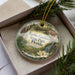 A decorative ornament in a box, featuring a scenic image of Ravine Gardens State Park, Florida.