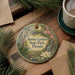 a round ornament with a floral design, hanging on a wooden surface. The ornament has text that reads "Ravine Gardens State Park, Florida".