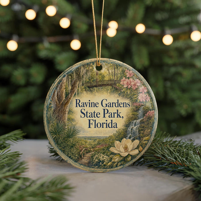 A circular ornament with a scenic illustration of a park, featuring a waterfall, flowers, and greenery, hangs in front of a blurred background of trees and lights.